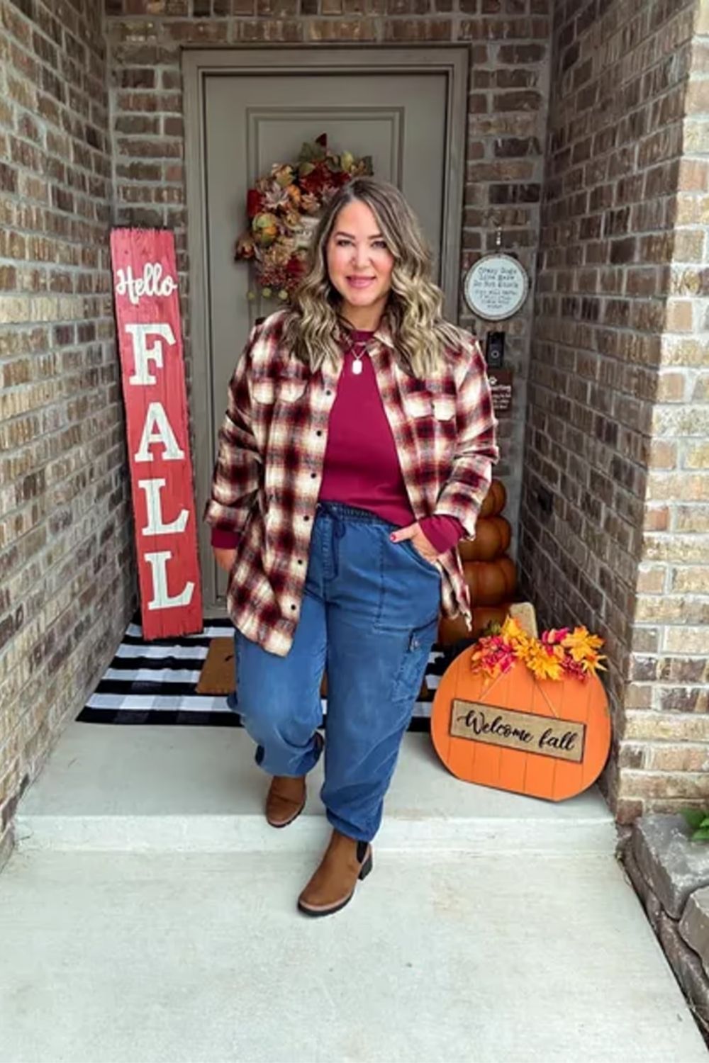 Embracing a cozy, autumnal vibe, this outfit combines a warm plaid jacket with a rich burgundy top, cuffed jeans, and ankle boots for a casual yet stylish look perfect for a fall day.