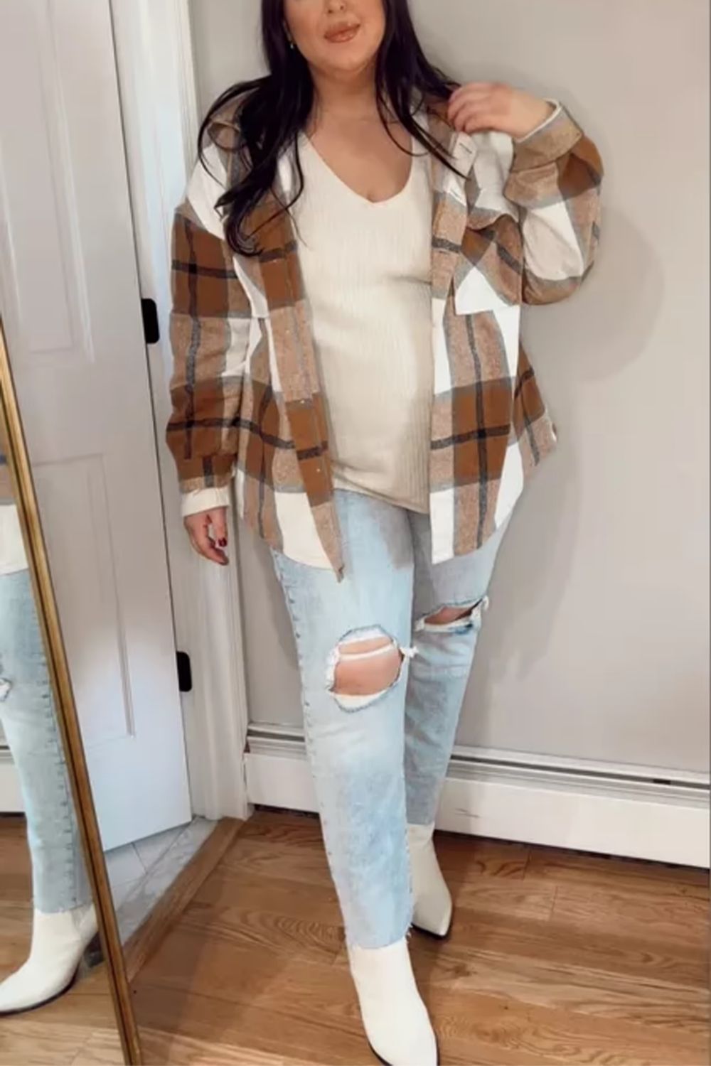 The oversized plaid shirt offers a trendy, laid-back vibe, complemented by casual yet stylish ripped jeans, and the cohesive color palette ties the look together, adding to its overall aesthetic appeal, while white boots provide a fresh and modern edge.
