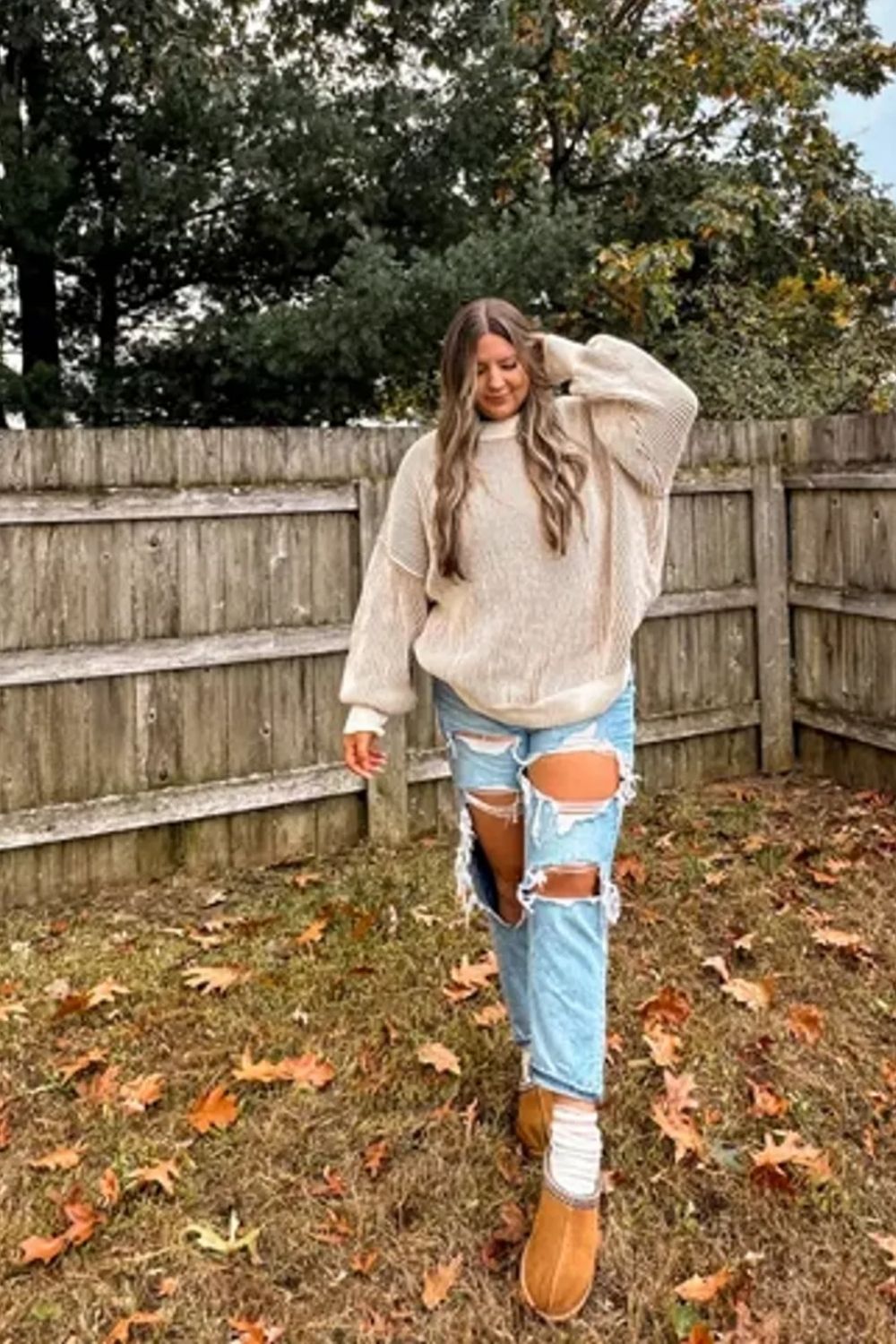 The oversized, chunky knit sweater creates a cozy, relaxed vibe perfect for fall, complemented by ripped denim for an edgy contrast and warm-toned boots that tie the look together.