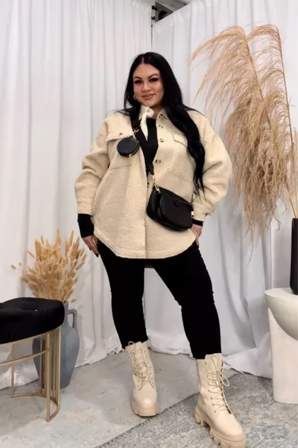 The cream sherpa jacket and black pants in this ensemble create a stylish contrast, adding both casual and fashionable elements, while coordinated cream boots and a crossbody bag enhance both function and a cohesive aesthetic.