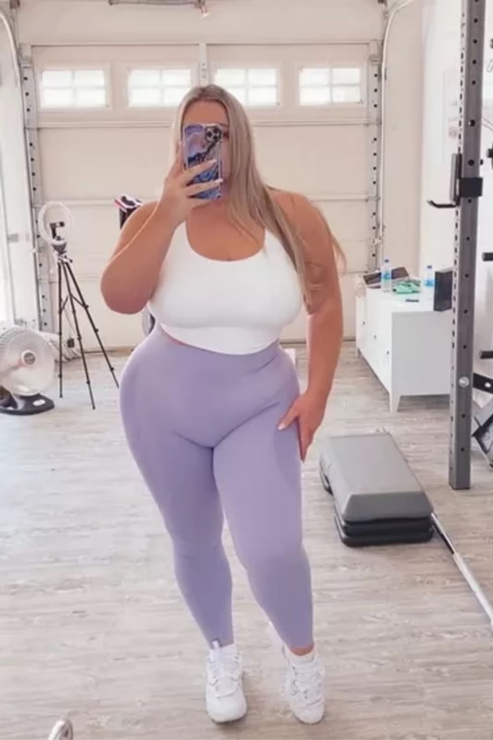 Practical and stylish with a fitted white tank top, high-waisted lilac leggings, and crisp white sneakers for a chic, sporty look suitable for any occasion.
