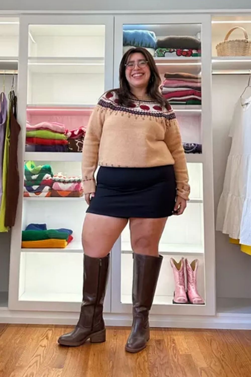 Presenting a chic and cozy style, this outfit features a warm-toned, patterned sweater for visual interest, a black skirt for sleek contrast, and knee-high boots that complement the ensemble, adding an elegant and fashionable touch, seamlessly tying the look together.